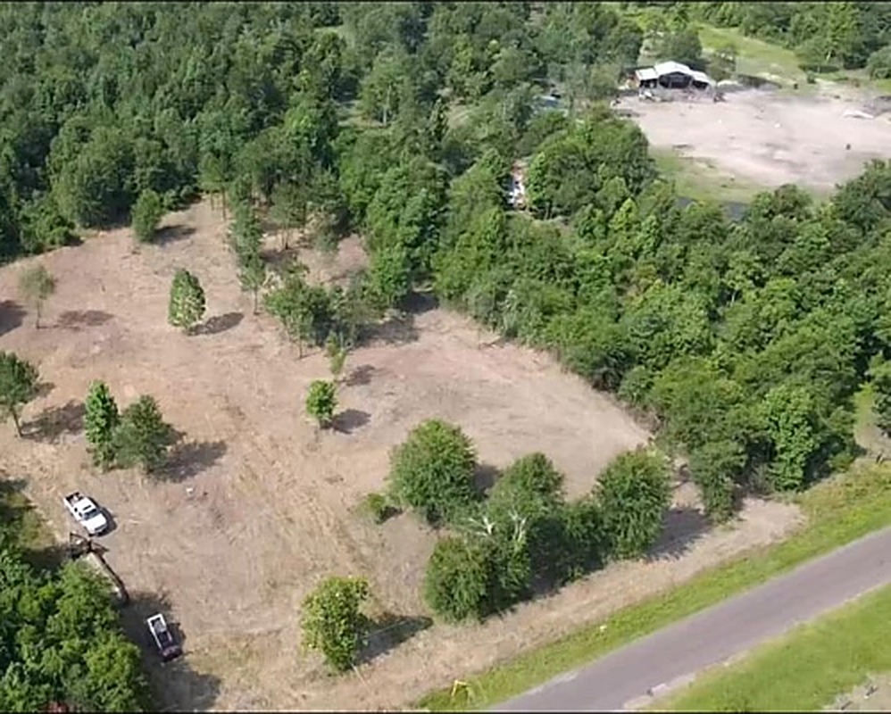 Drone photo of cleared acreage and access lanes cut through heavy brush